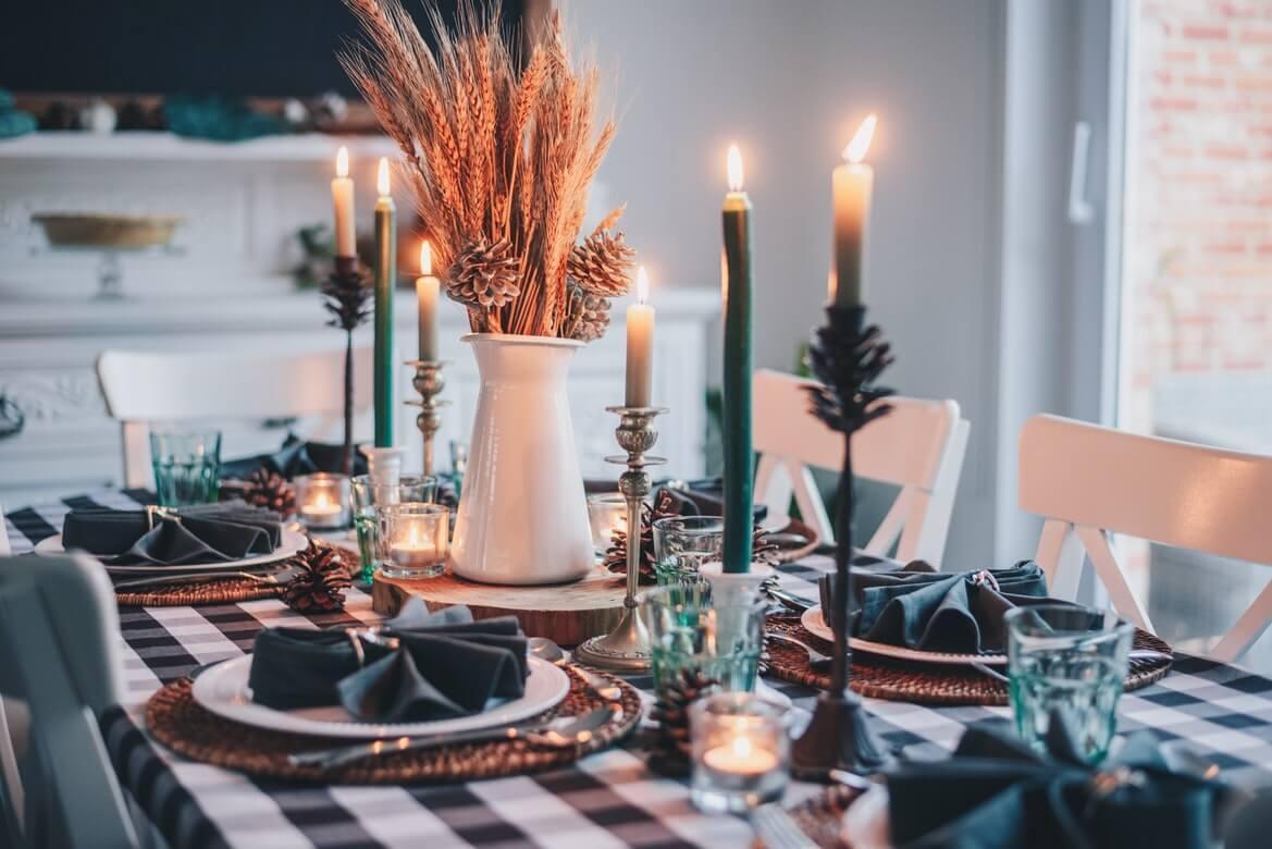Christmas table setting with black and white checkered table cloth, wicker place mats, and green accents
