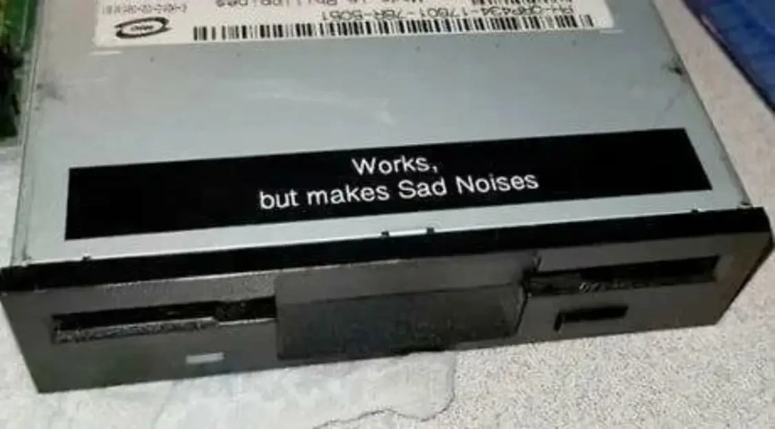 Photo of an old CD-ROM Drive labeled “Works, but makes Sad Noises”