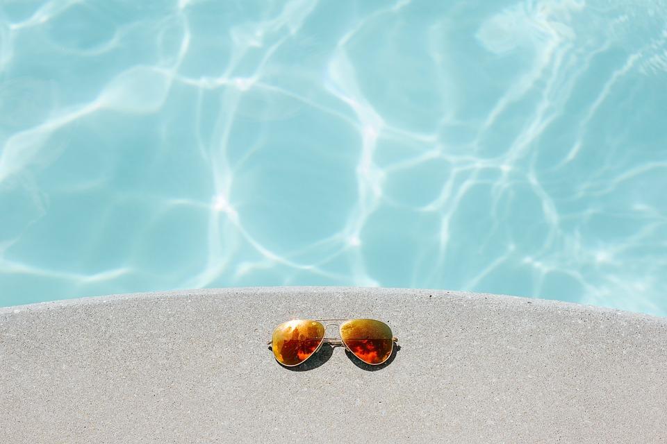 Orange sunglasses on cement by a pool