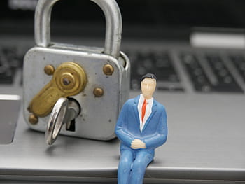 Lock yourself against Cyber Crime Padlock with male toy in suit sitting on laptop represetning possible cyber crime
