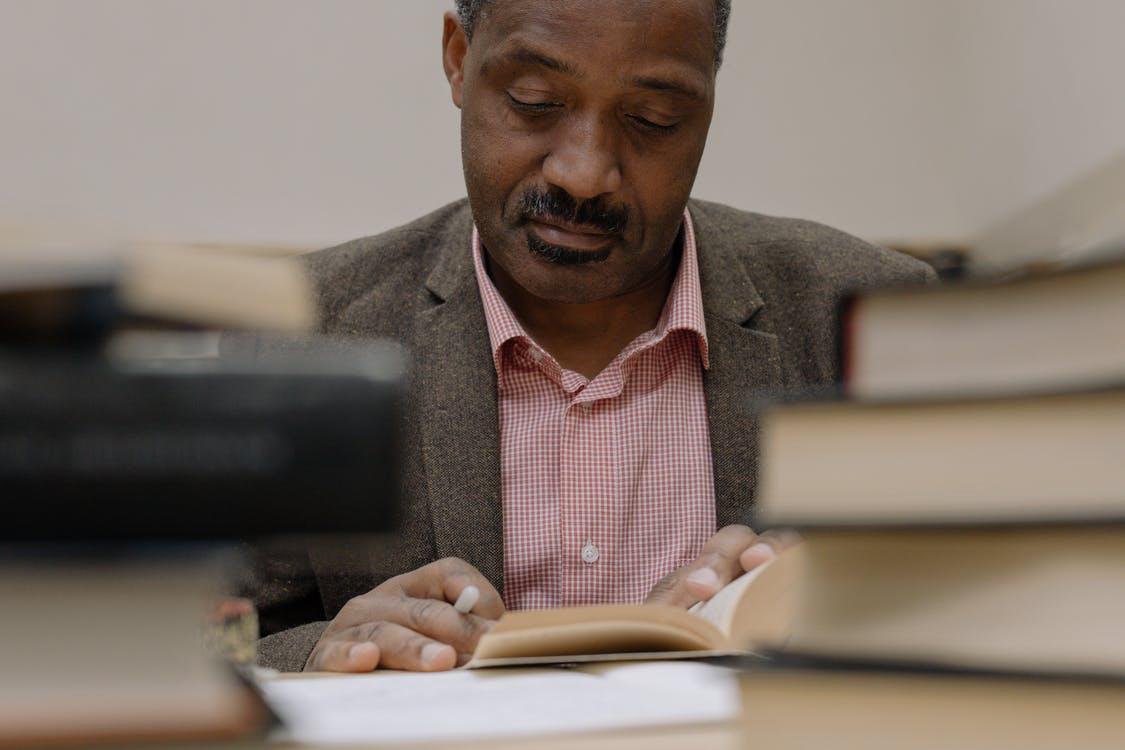 Professor reading a book surrounded by more books