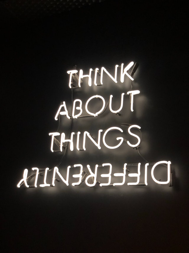 The words "Think about things differently" are lit up in neon with the word "differently" upside down.