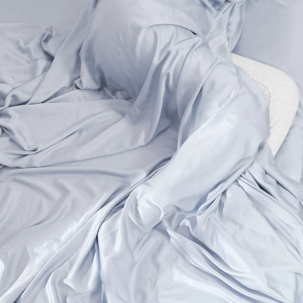 Sleeping person wrapped in arctic blue cooling bamboo sheets by Hush.