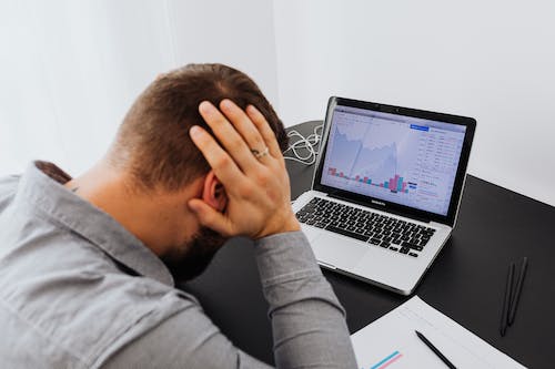 Free Man with Laptop on Desk Terrified by Stock Market Chart Stock Photo