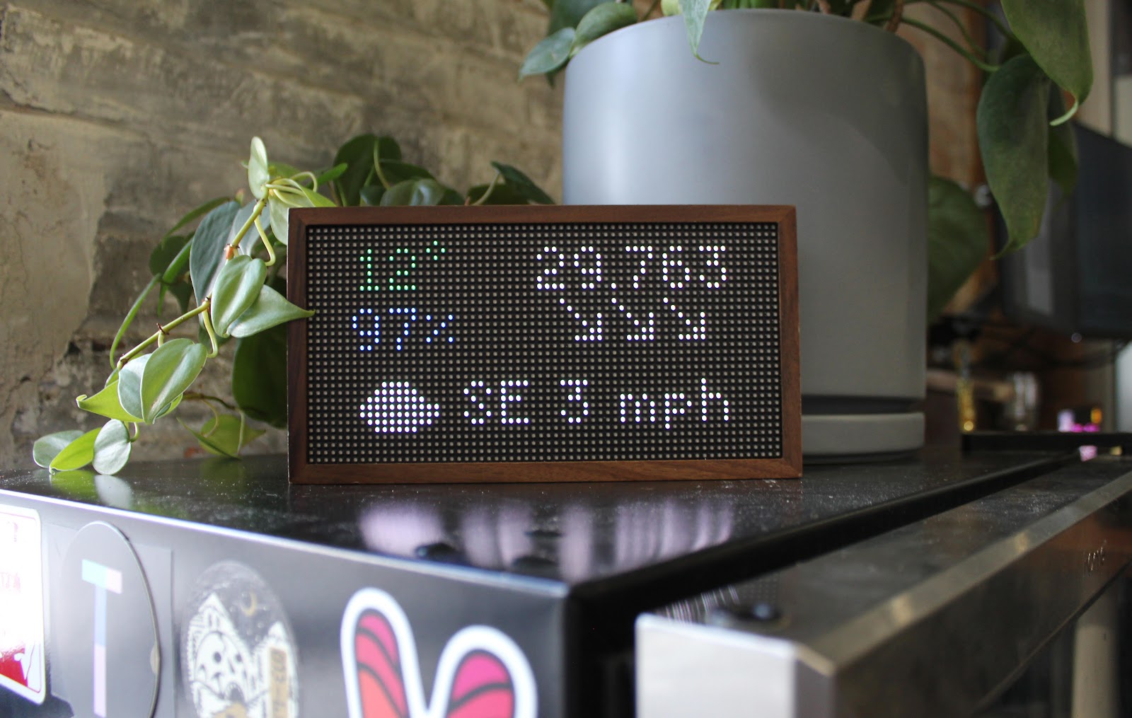 Tidbyt display showing weather data on desk. 