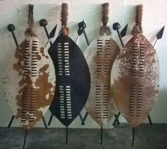 Four almond-shaped cowhide shields leaning against a wall.