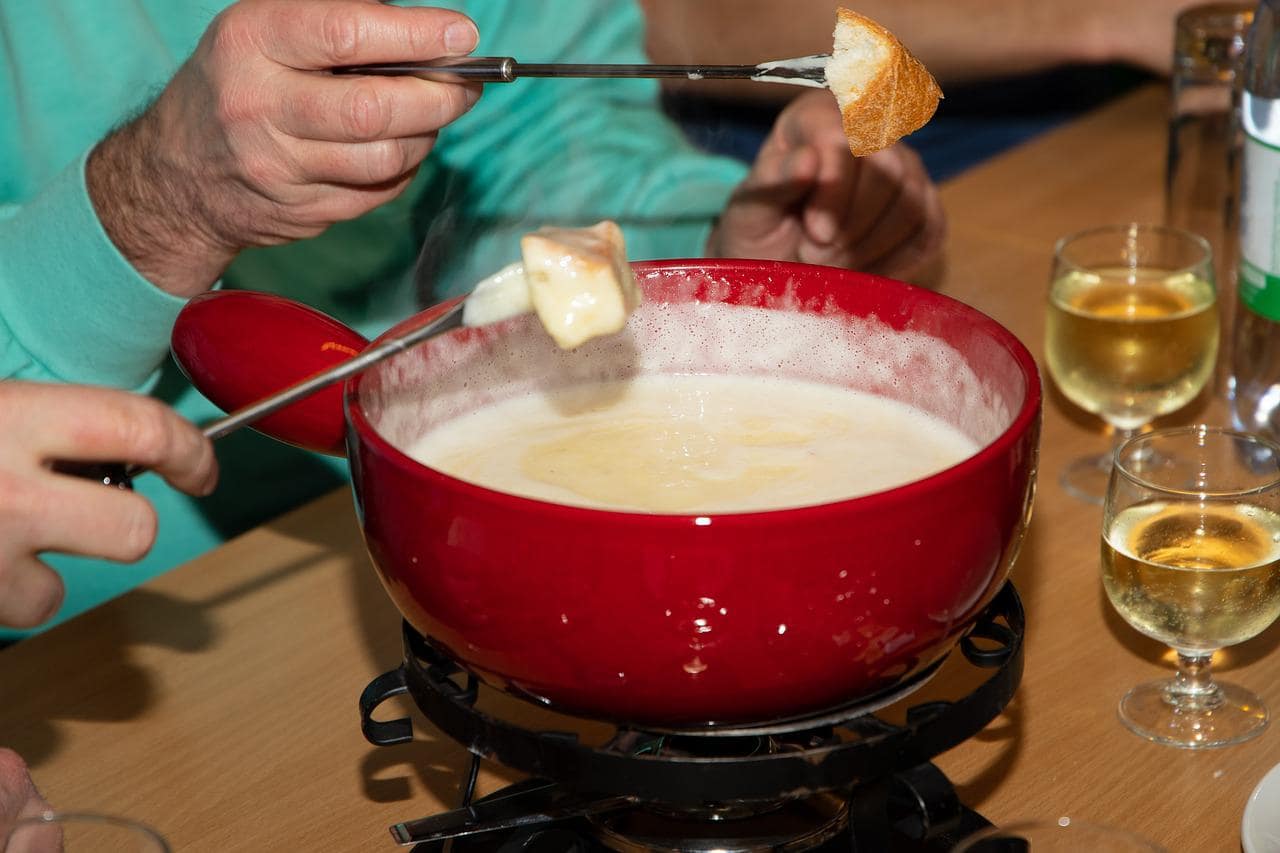 People dipping bread in a fondue pot