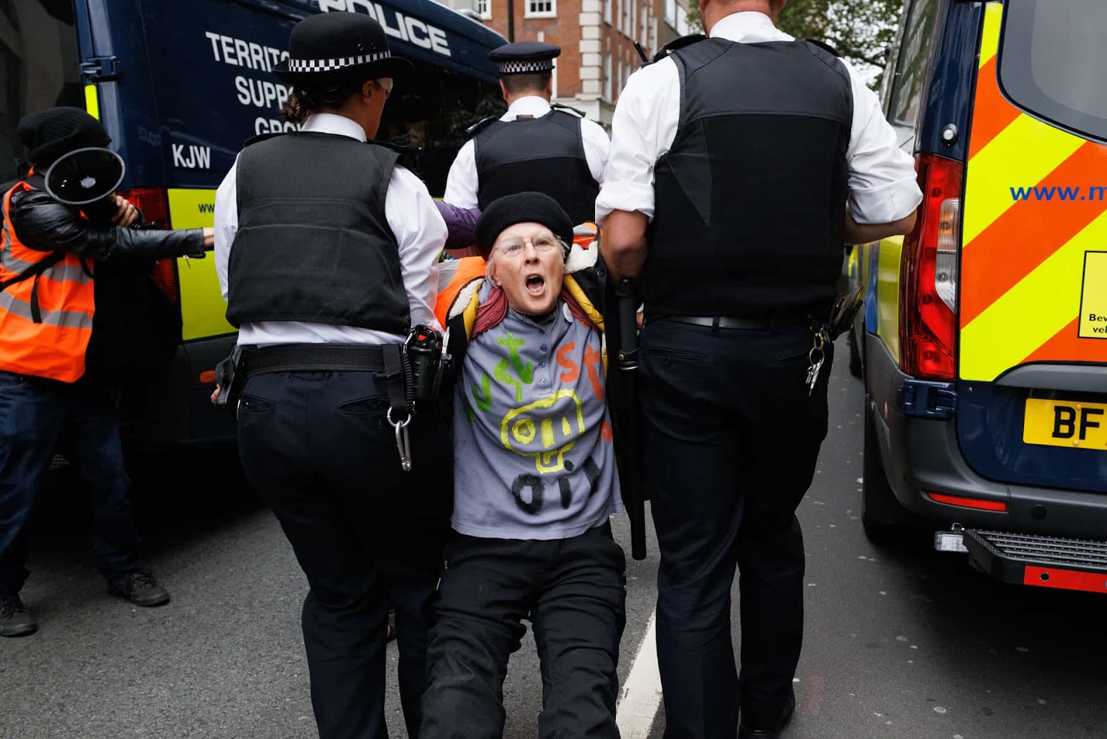 An activist shouts to camera as he is dragged away into a police van