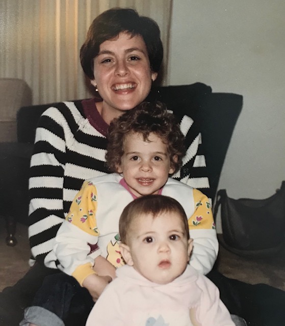 Baby Alisa with her sister and mom all sitting in each other's laps.