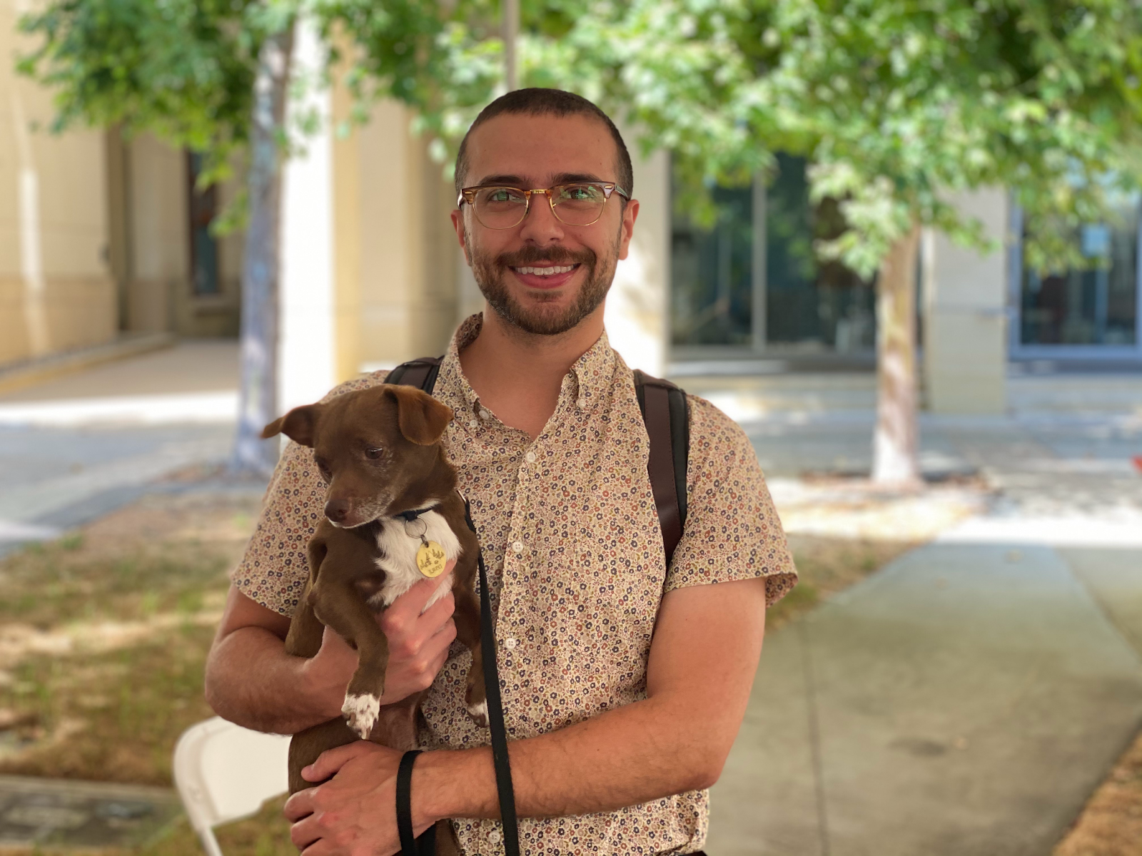 Stanford lecturer Max Ashton poses for a portrait holding his small dog Bjarki.