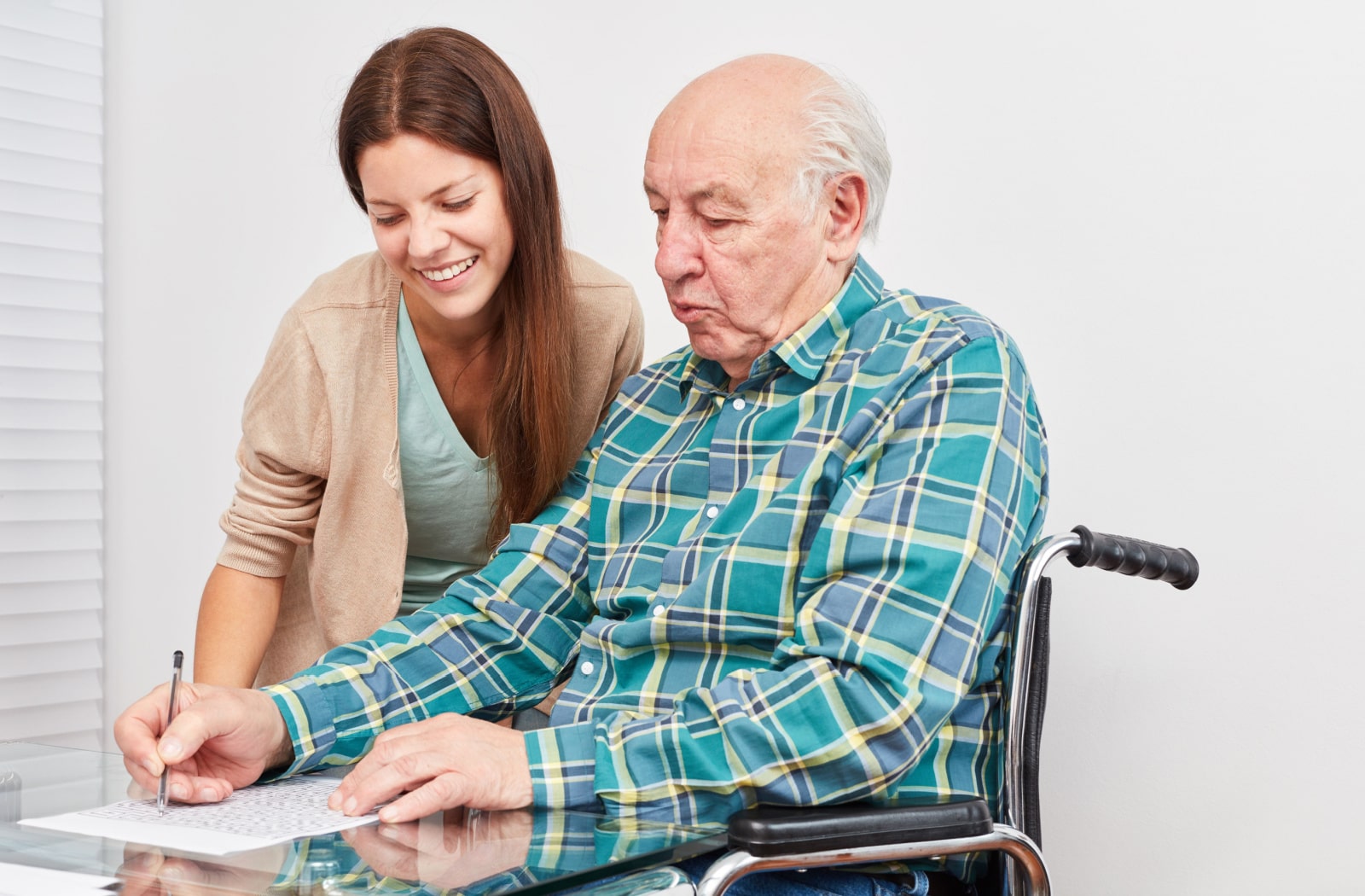 A female nurse talks to a memory care resident as he works on a puzzle