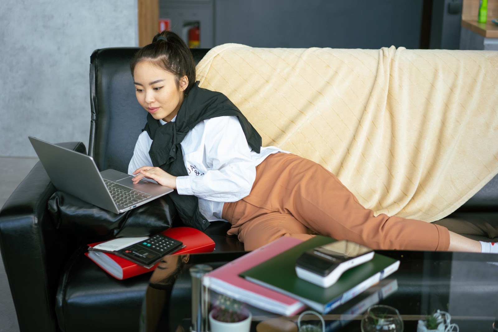 A girl  lying on a couch looking at her computer -Interning Remotely - 7 Most Unexpected Challenges 
Photo by Mikhail Nilov from Pexels