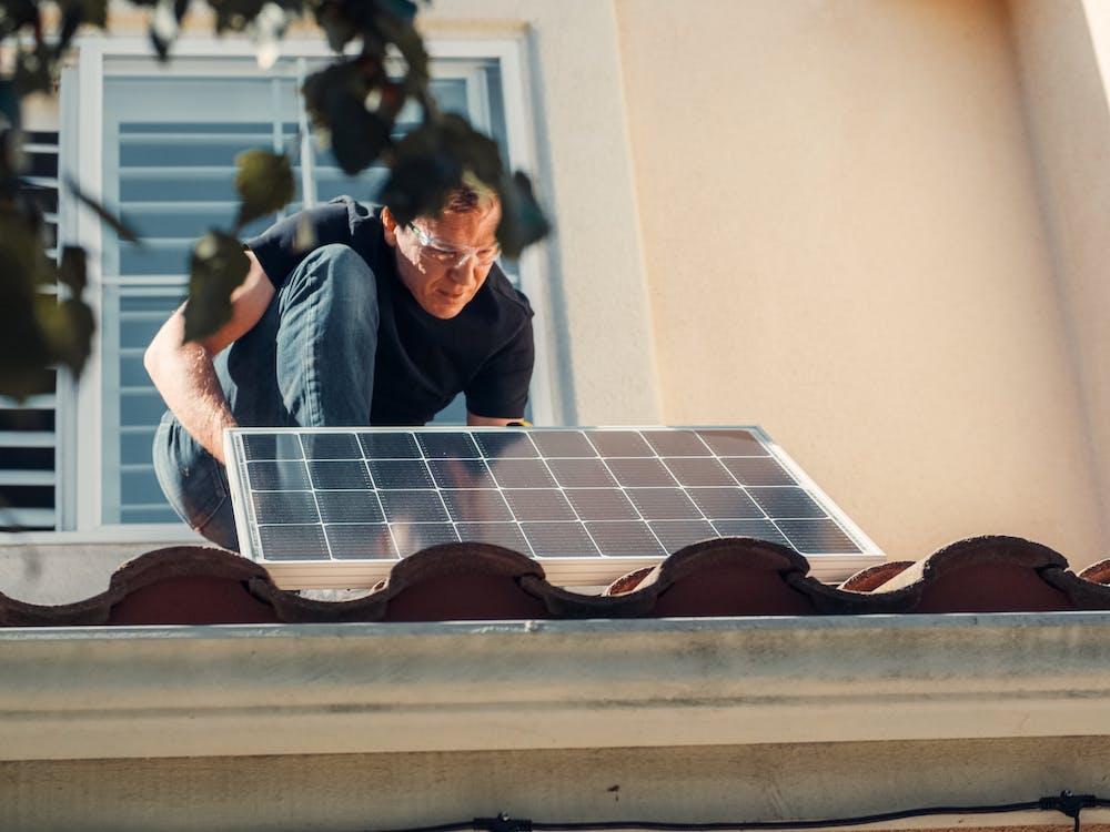 Free A Man in Black Shirt Installing a Solar Panel on the Roof Stock Photo