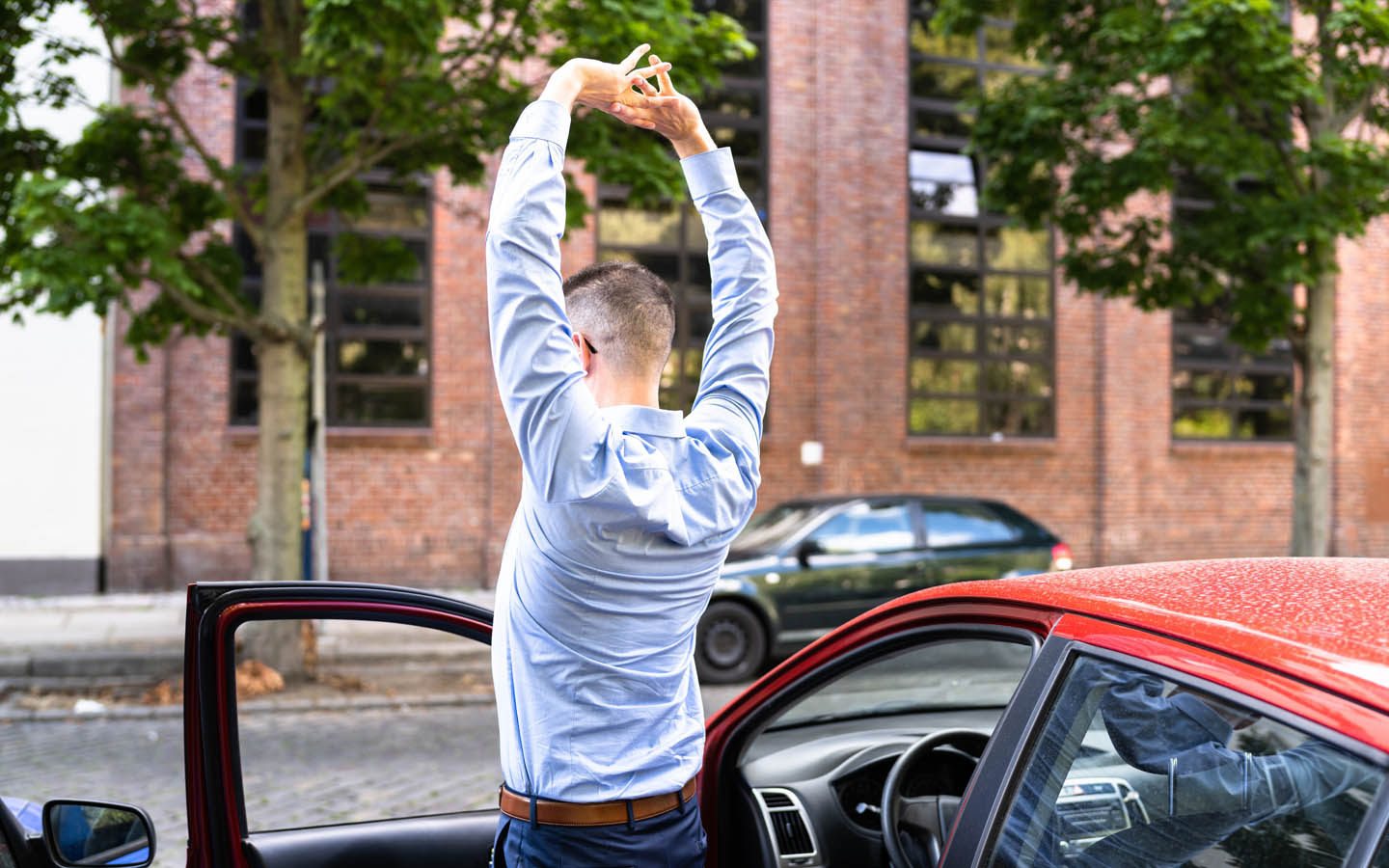 man stretching outside car