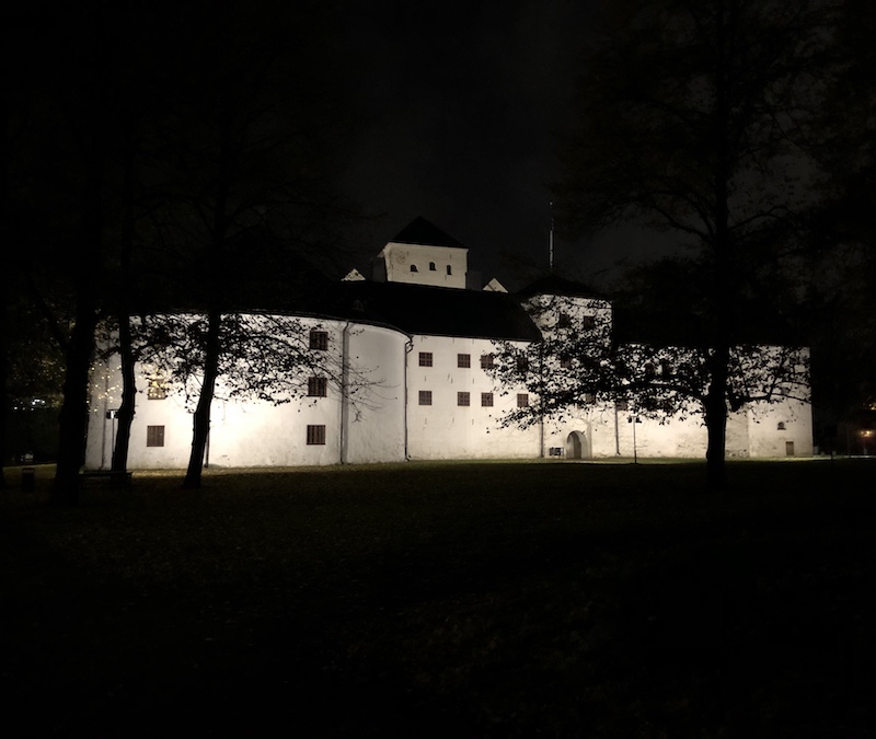 Valaistu Turun linna hohtaa mustassa yössä Linnanniemellä. 