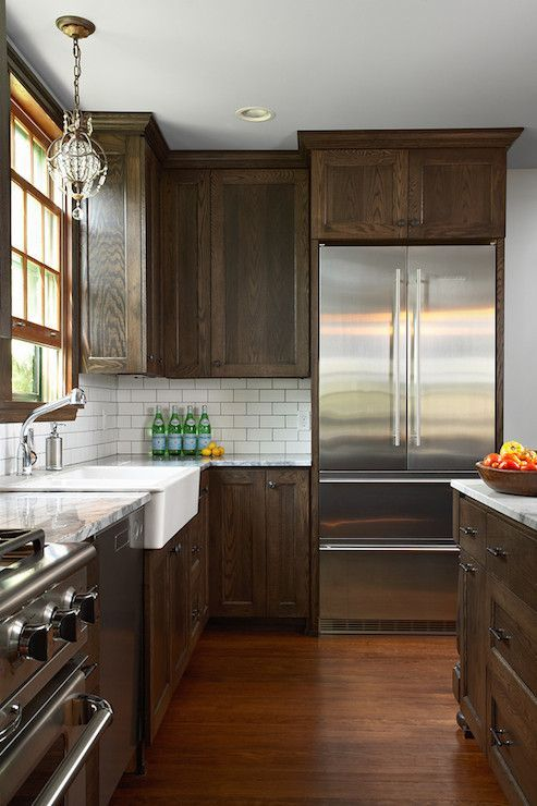 dark stained wood shaker cabinets are complemented by stainless steel appliances, dark wood floors and white subway tile backsplash