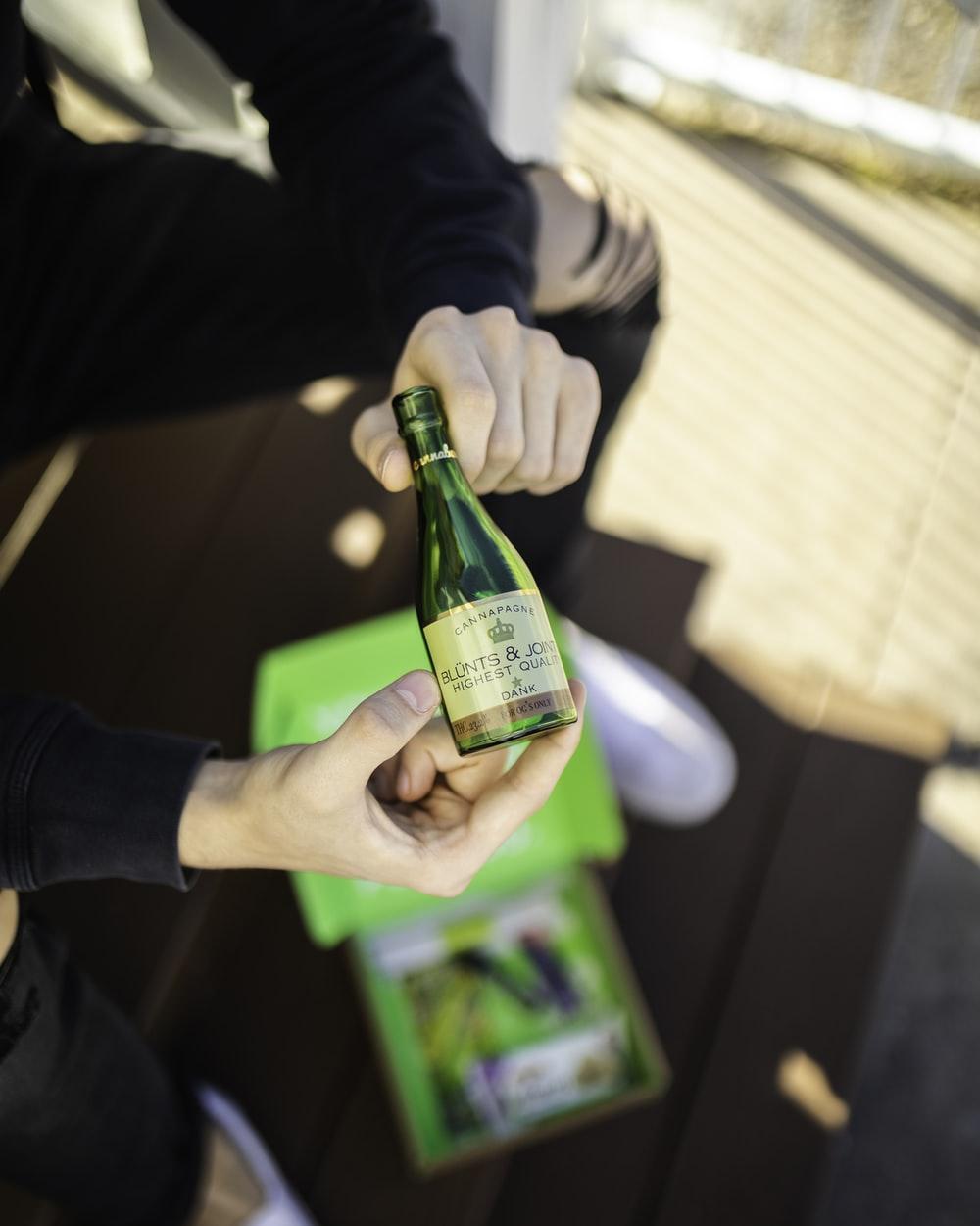 person holding green glass bottle