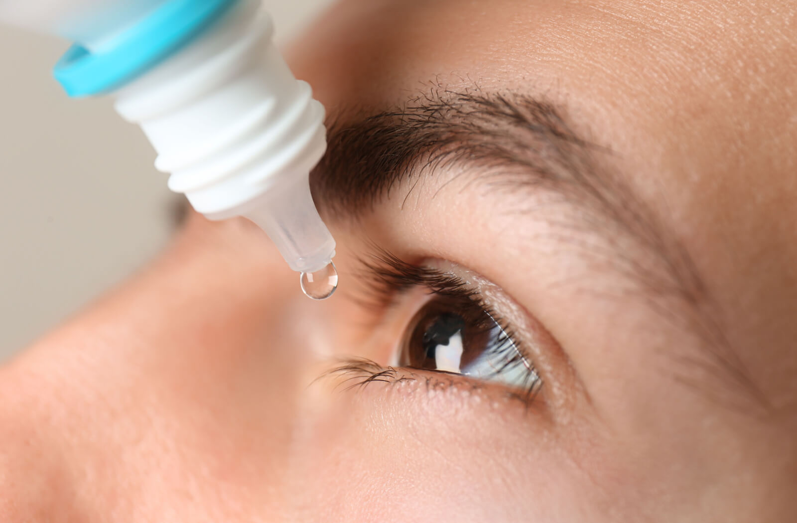 A close-up of a person using lubricating drops to keep her eyes moist while using her contact lenses