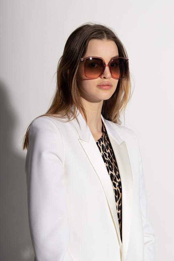 Woman in formal attire wearing large-frame, rectangular sunglasses