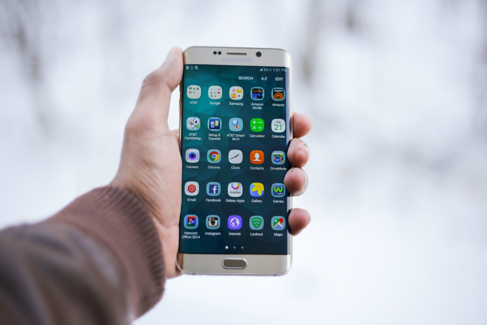 Man holding a mobile phone. The screen is filled with app icons.