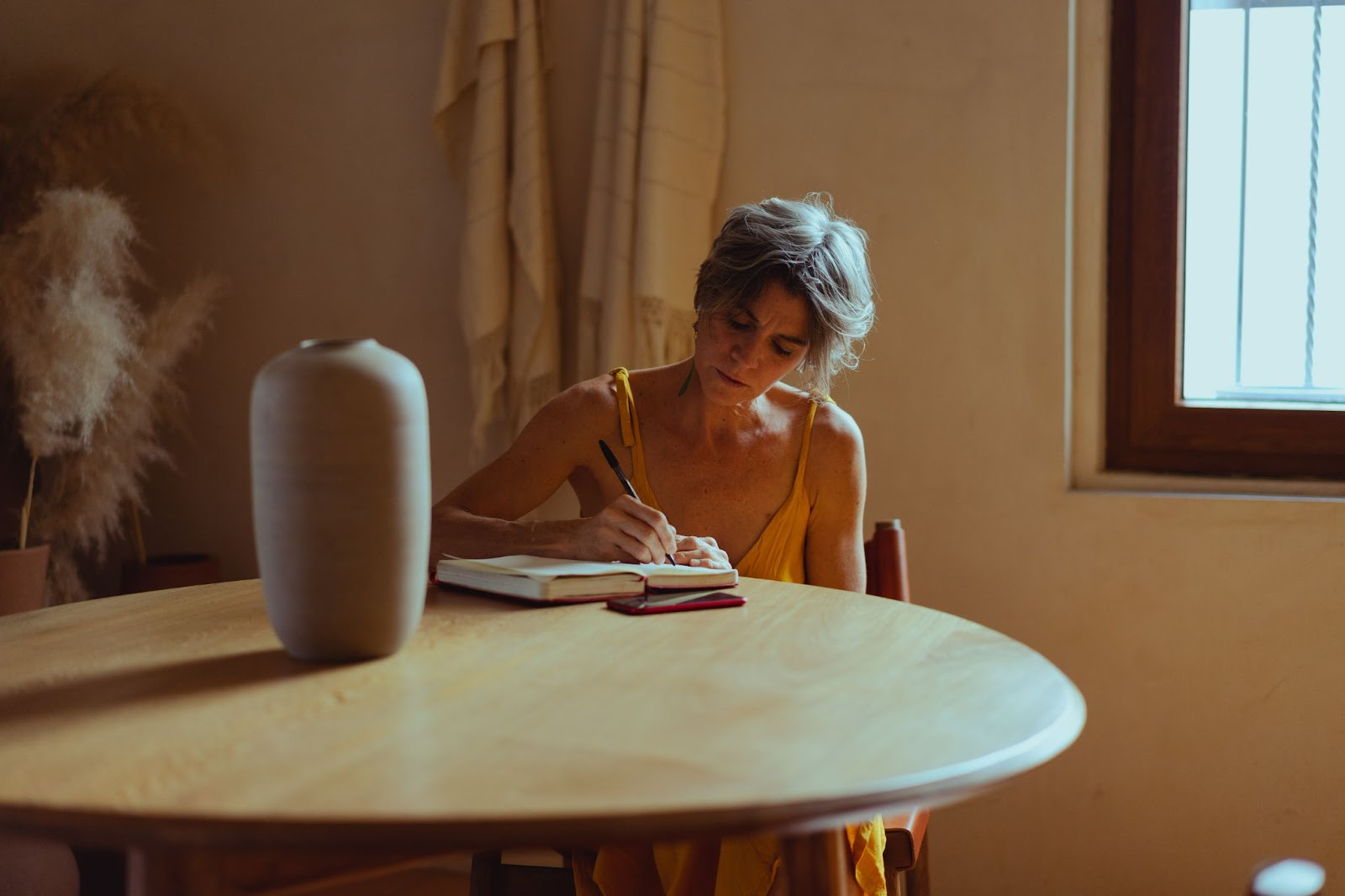 image of woman writing in notebook in dining room
