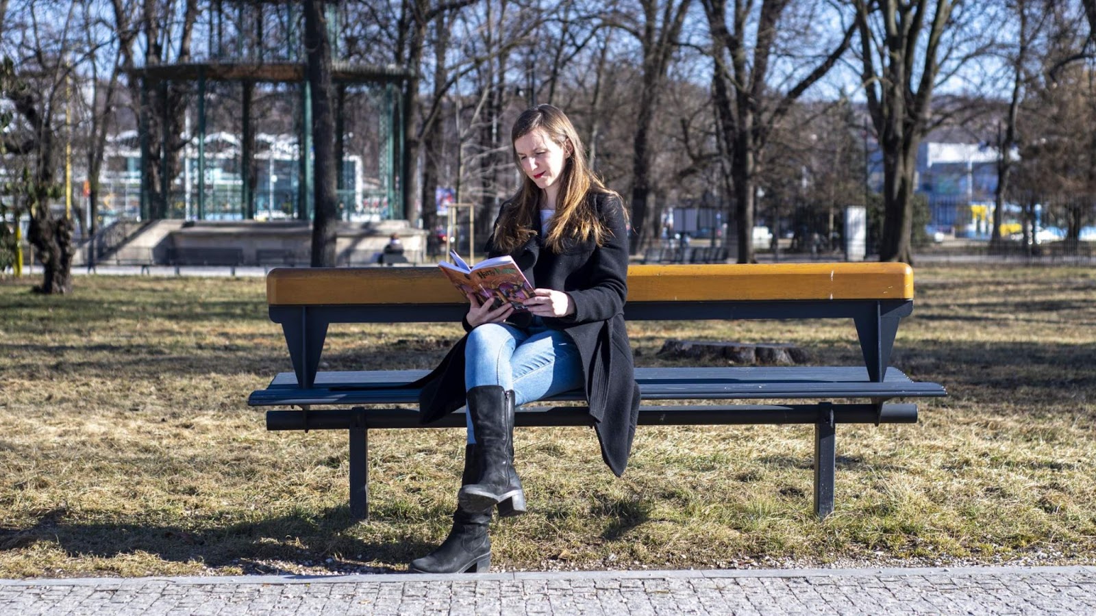 Martina sedí na lavičke v parku a číta Harryho Pottera v portugalčine.