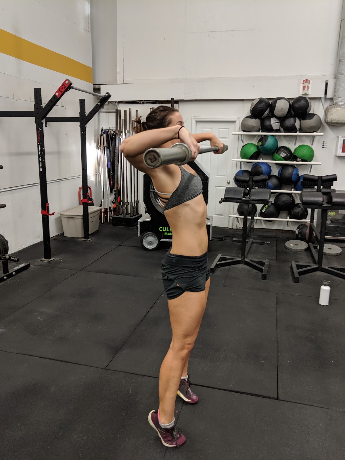 woman in gym doing a snatch pull with barbell