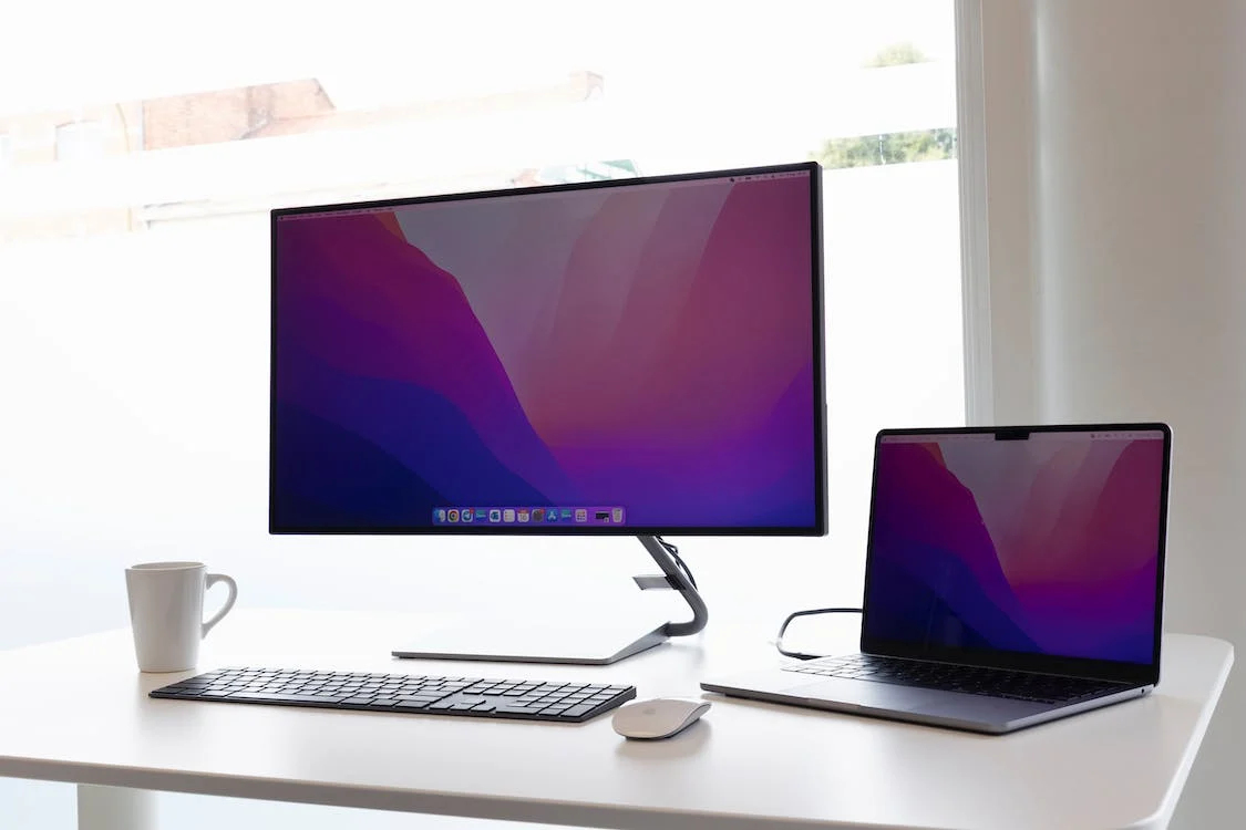 Computer and laptop on the white table
