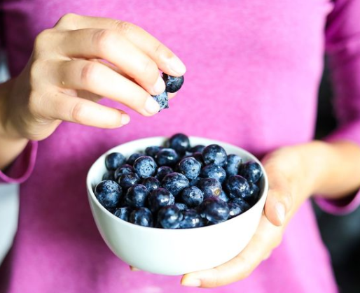 Closeup of someone holding a bowl of blueberries