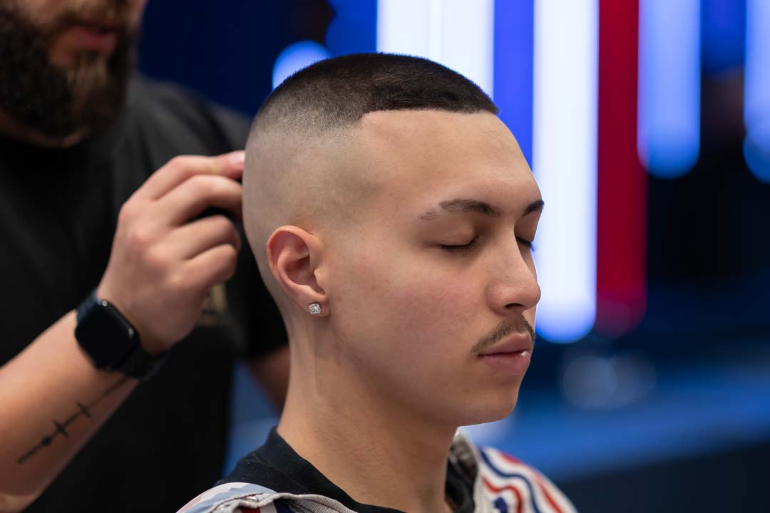 a guy in a salon with a barber working on his hair