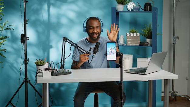 African american vlogger using smartphone to film podcast
