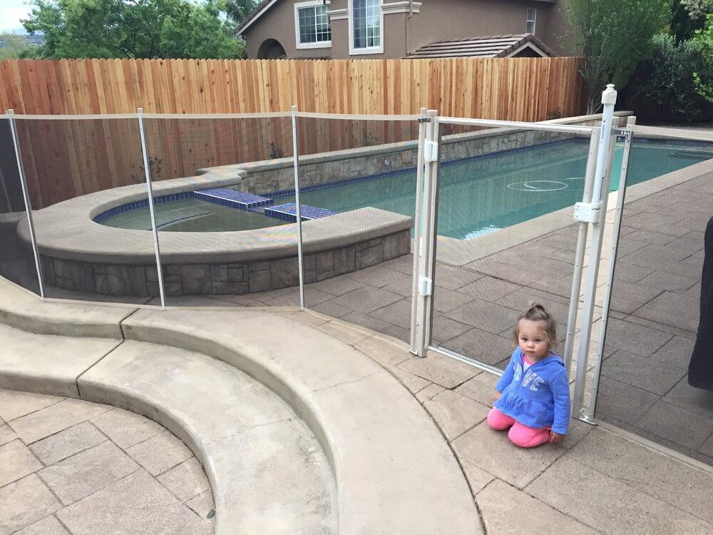 Toddler sitting in front of a white installed mesh pool fence