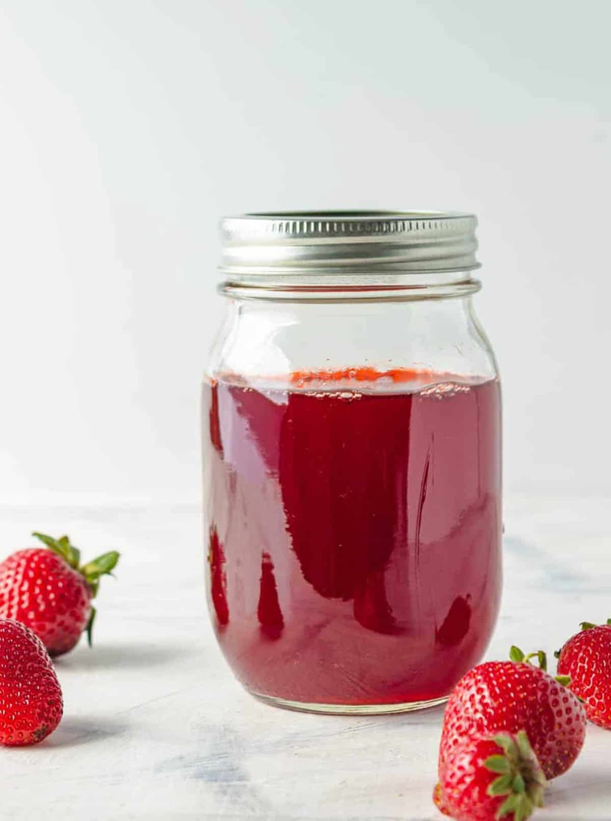 Homemade easy strawberry simple syrup for drinks stored in a mason jar.