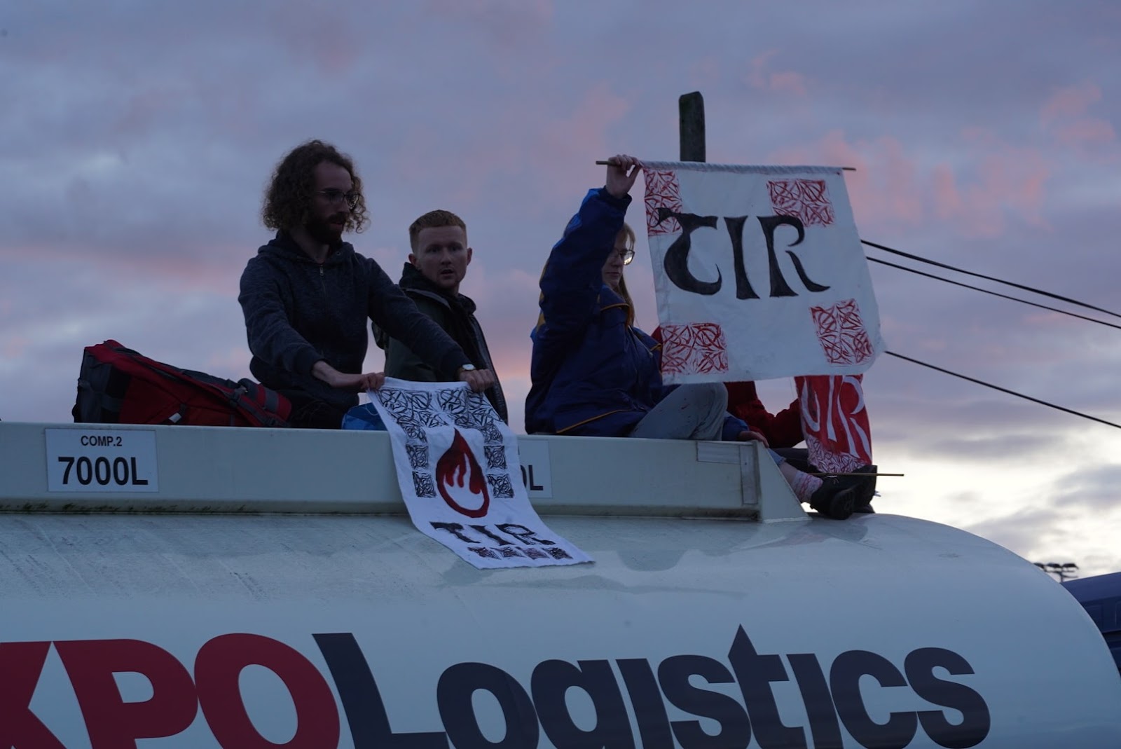 Young activists with This Is Rigged banners sit atop an oil tanker truck