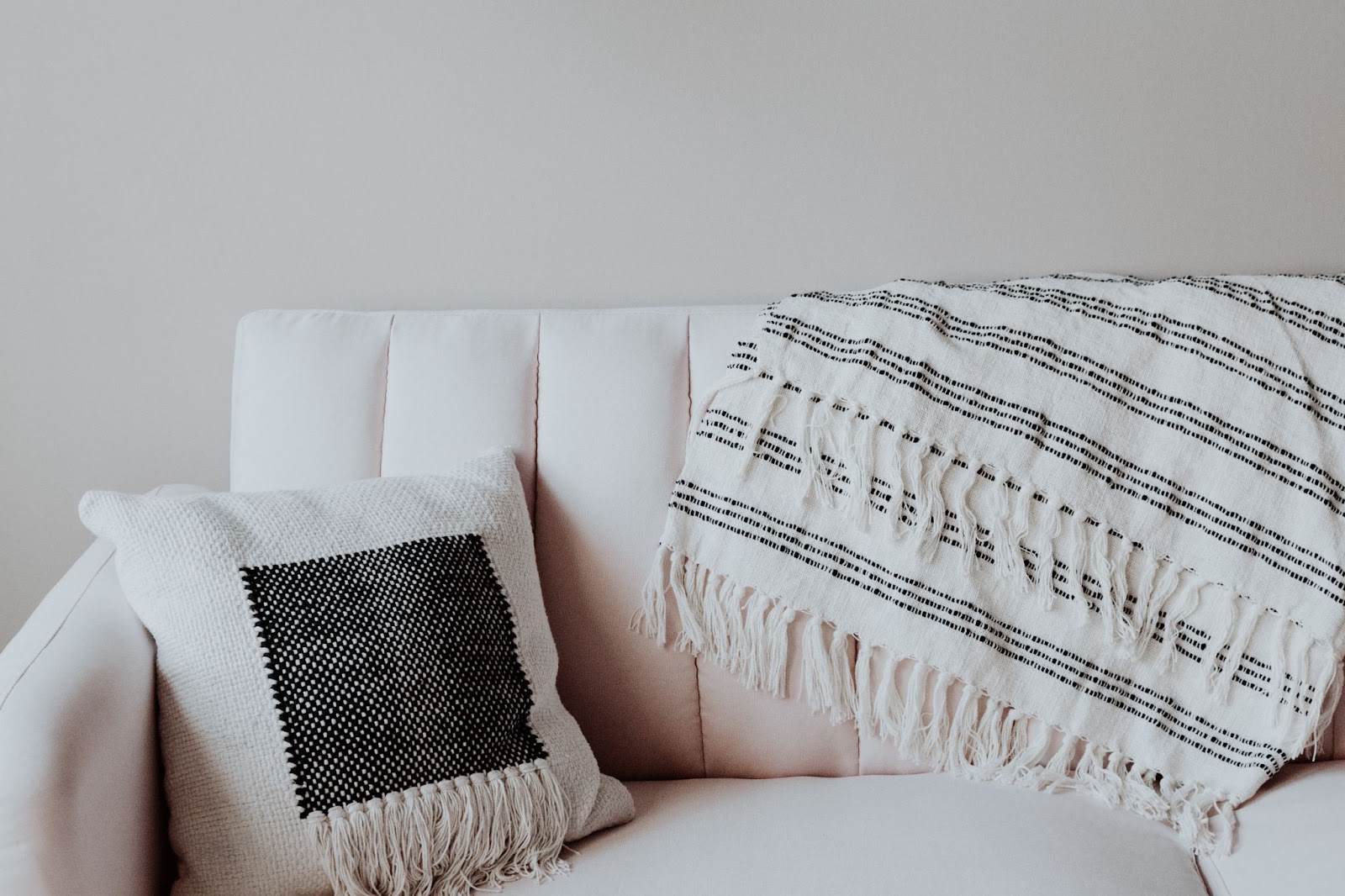 A couch with a pillow and a blanket, which are all white