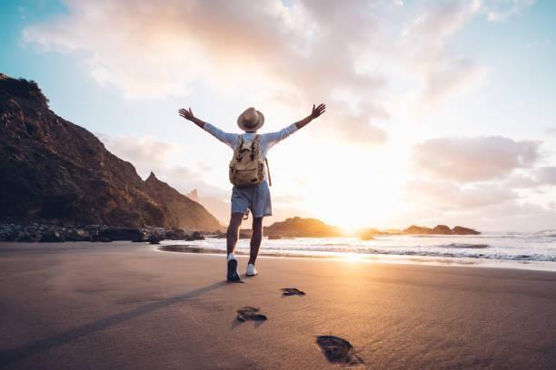 Young man arms outstretched by the sea at sunrise enjoying freedom and life, people travel wellbeing concept Young man arms outstretched by the sea at sunrise enjoying freedom and life, people travel wellbeing concept vacation stock pictures, royalty-free photos & images