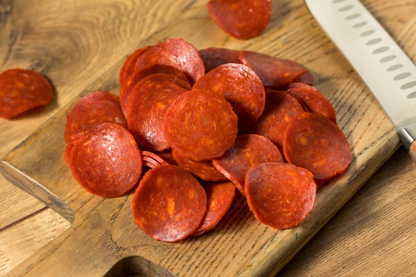 Heaps of pepperoni slices on a wooden board