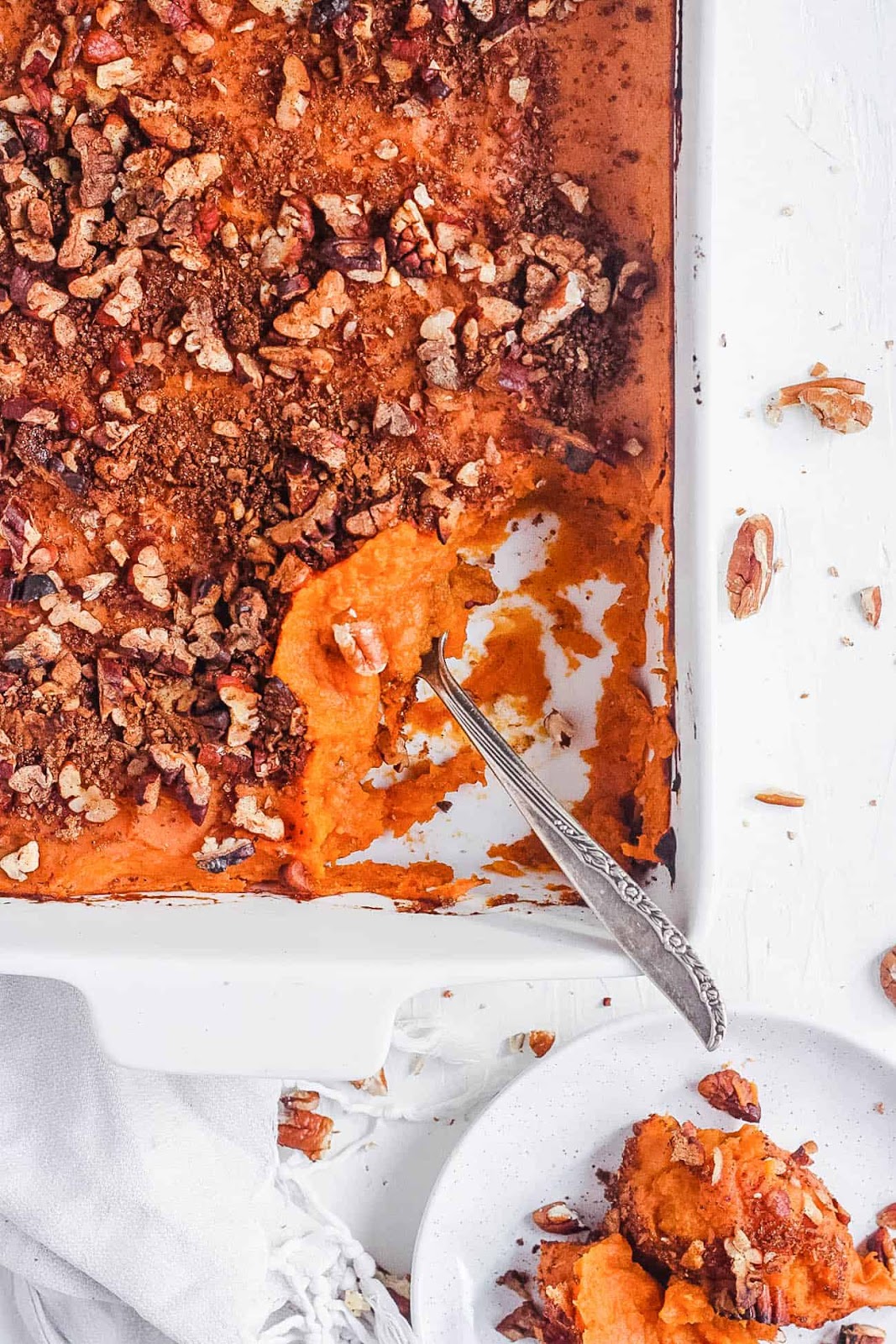Sweet potato casserole in a white serving tray topped with nuts.