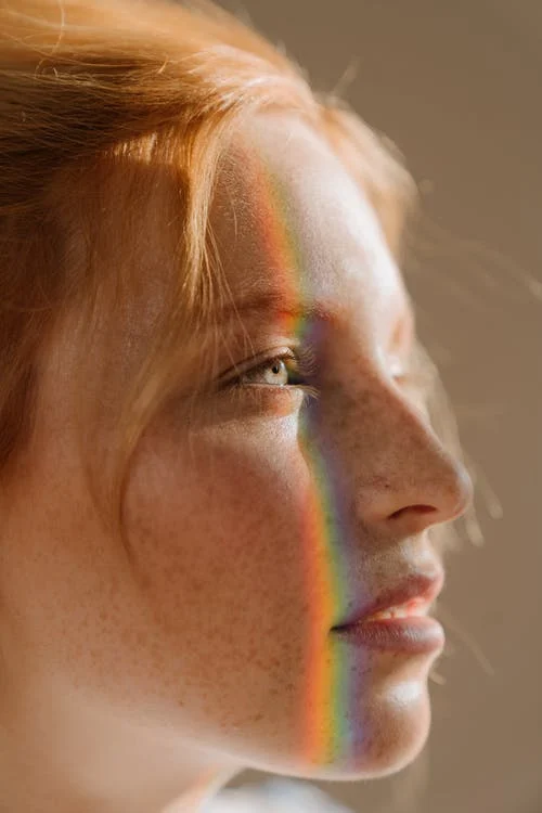 image depicting a woman with a rainbow glare on her face