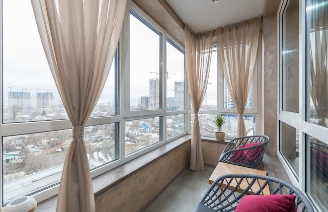 Consider purchasing balcony furniture for your small apartment that’s easy to maintain, such as these two minimalistic chairs with throw pillows.