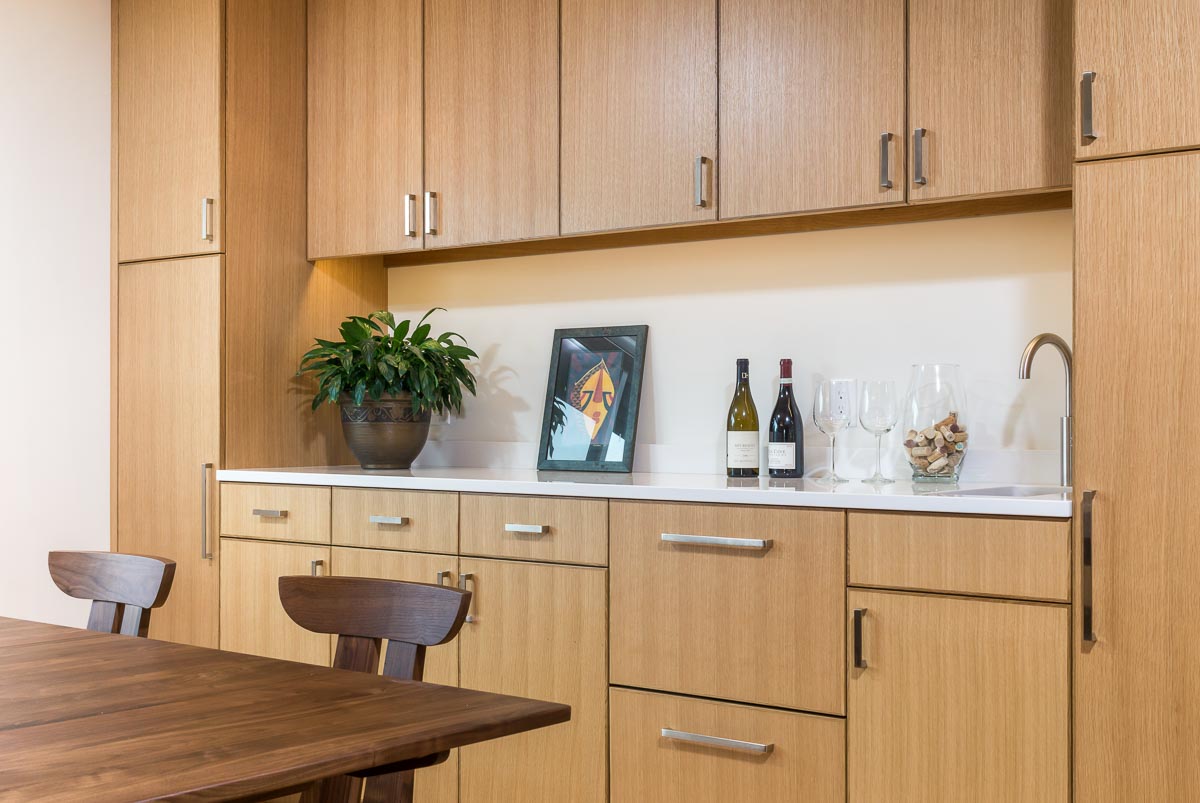 modern mid century dining room with wooden oak cabinets and a counter with a wine bottle on top