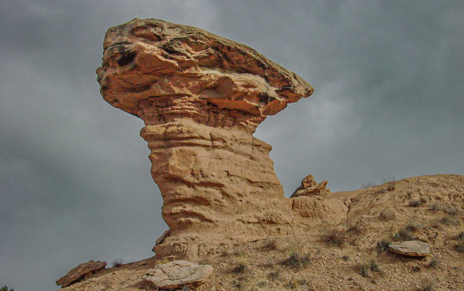 A large rock is supported by a column. 