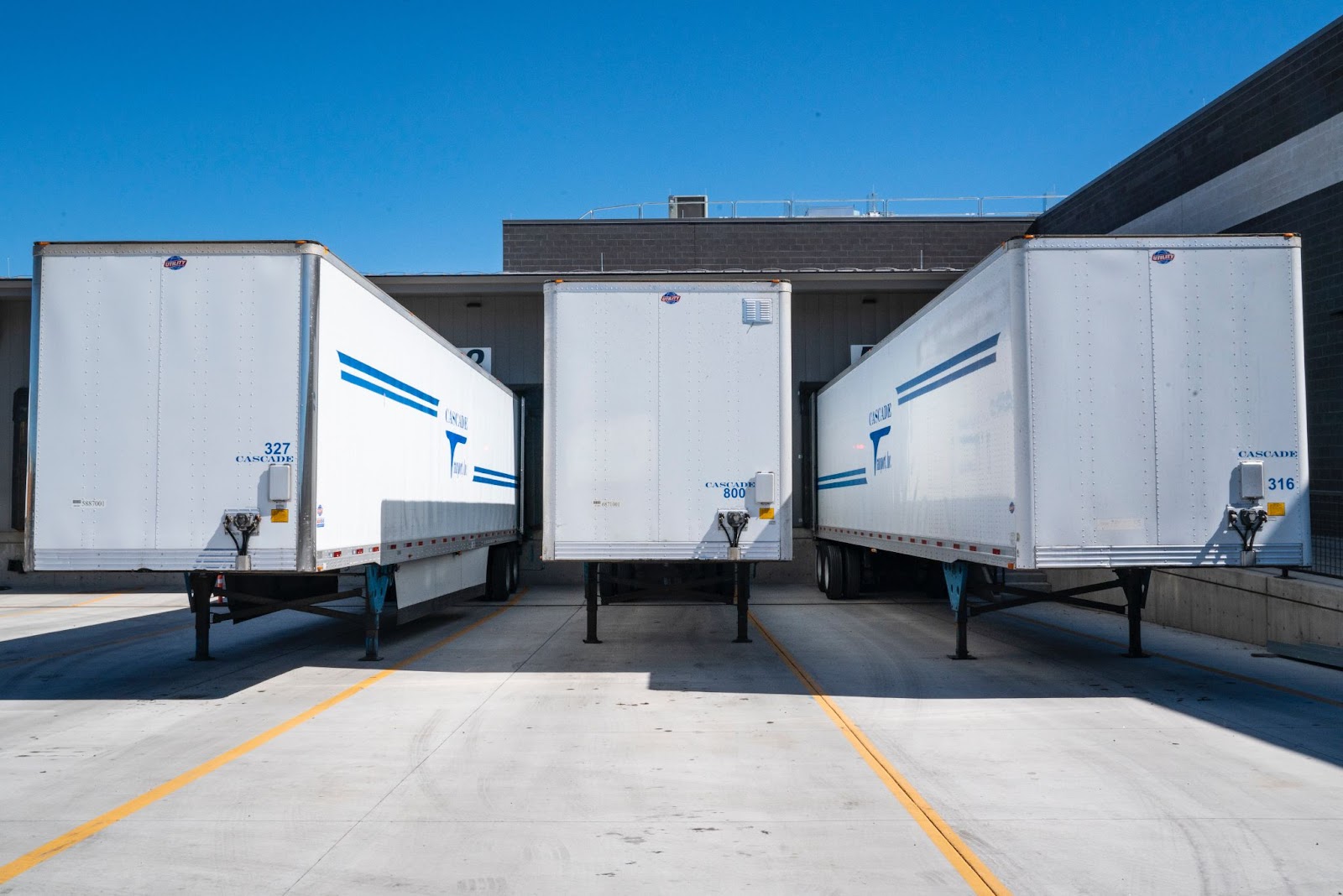 3 white tractor trailers lined up next to each other.