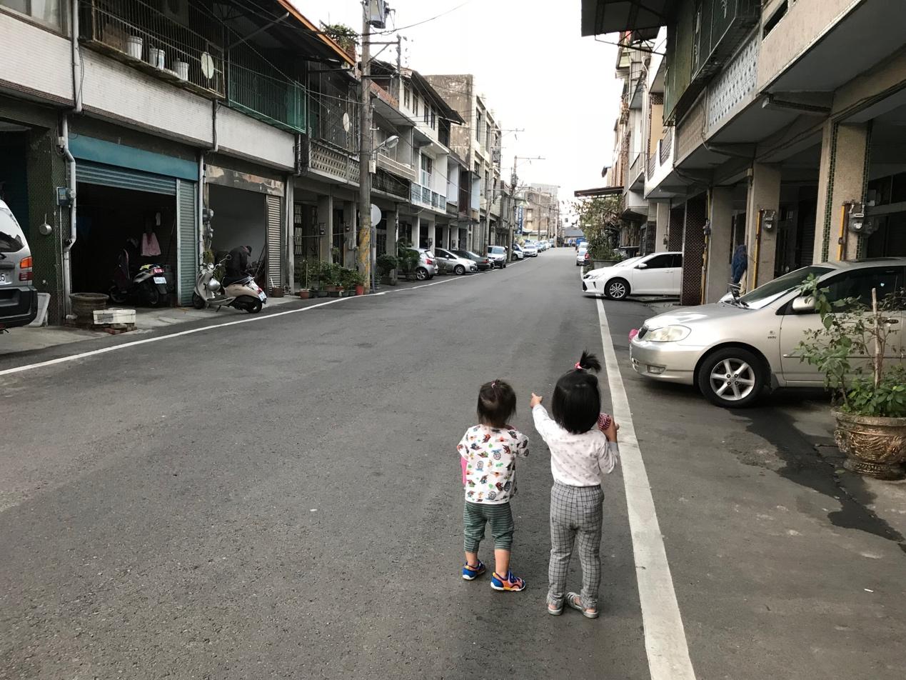Two children standing on a street

Description automatically generated