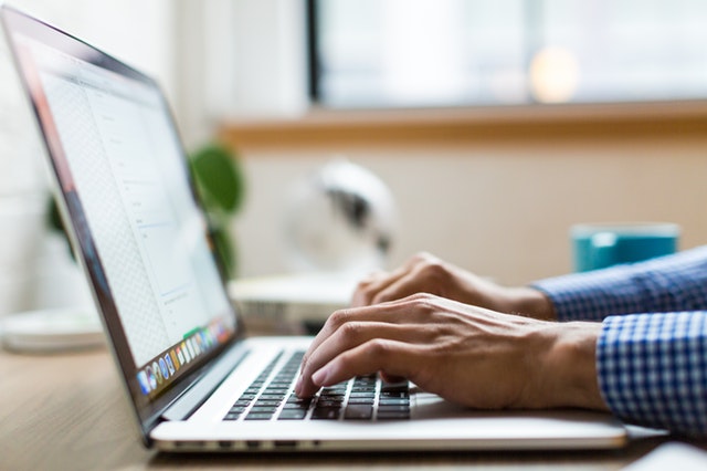 A Virtual assistant typing his blog post on a laptop