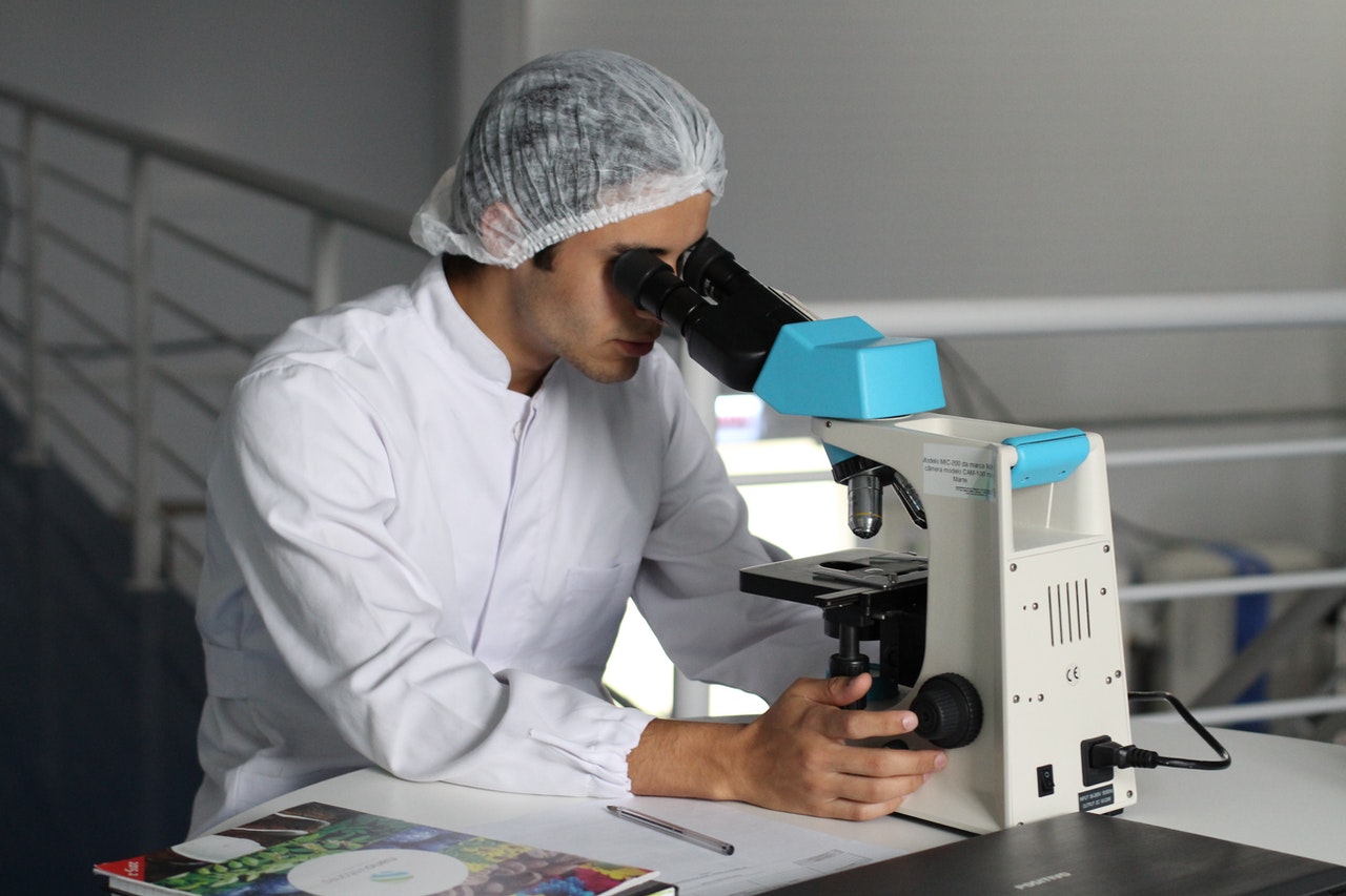 Biomedical engineer looking through microscope