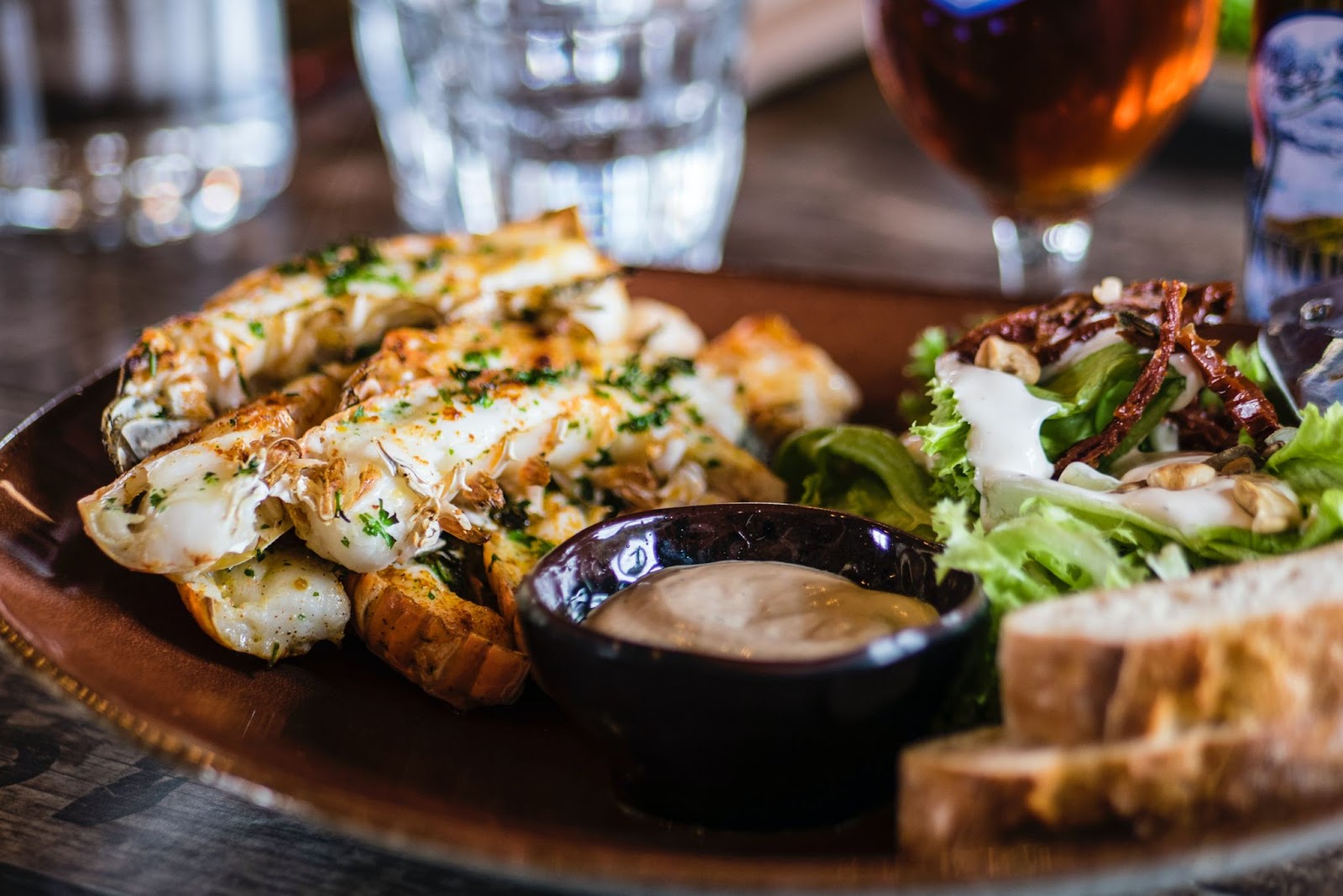 Plate of gyoza, sauce in a small dish, salad and pieces of focaccia bread. 