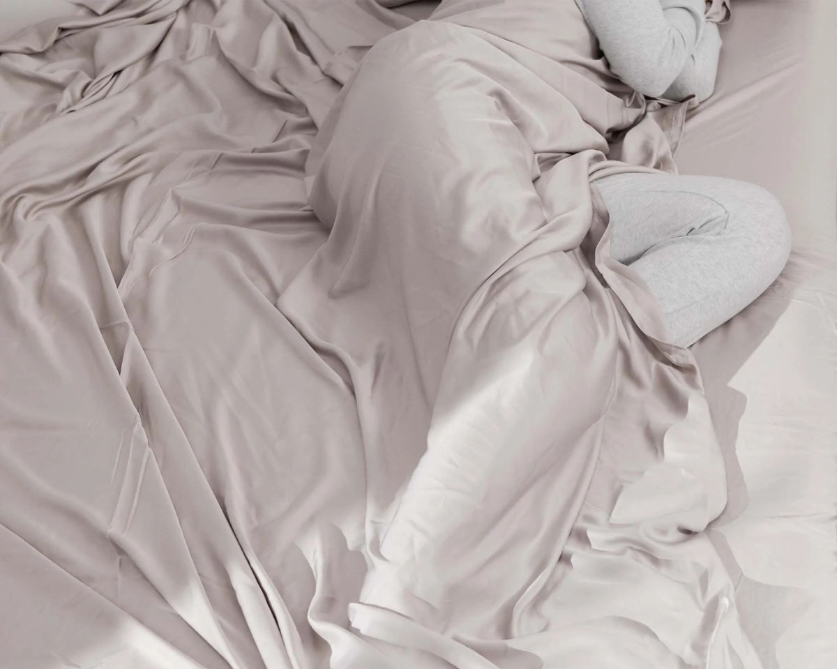 The lower half of a woman's body curled up in some silver sheets.