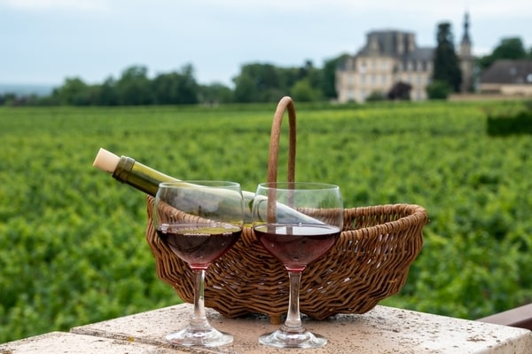 Glasses of Pinot Noir wine with a basket containing a wine bottle at the back