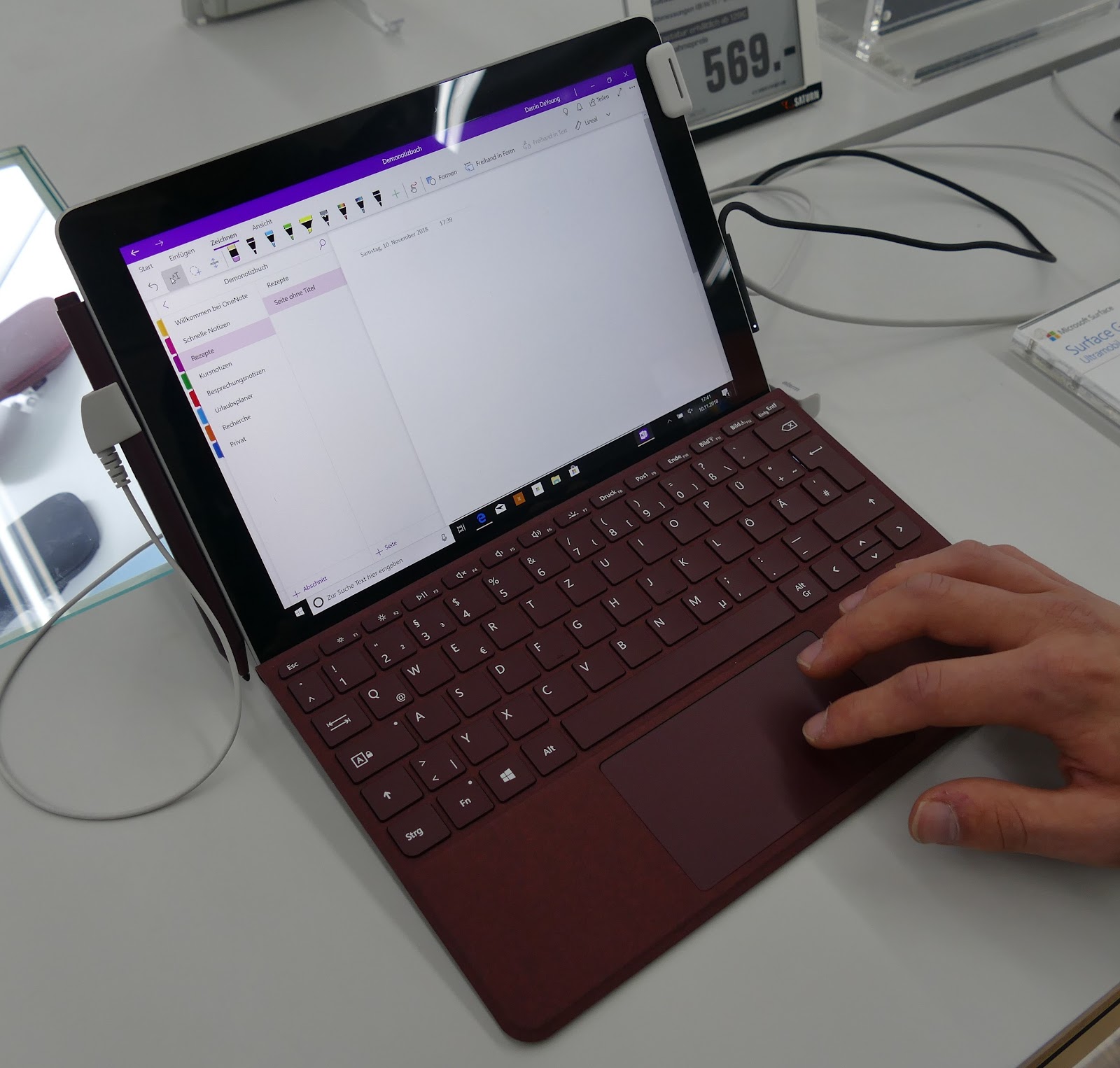 This image shows the laptop with open display in the hands of man in the white table.